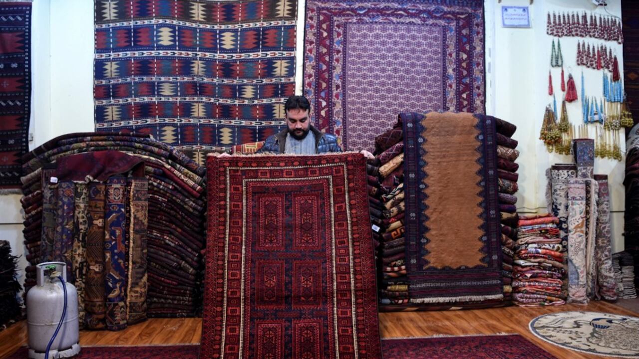 En esta foto tomada el 18 de enero de 2021, Abdul Wahab, un coleccionista de alfombras tribales muestra una alfombra durante una entrevista con la AFP en el interior de su tienda en la calle Chicken de Kabul. - Los cazadores de alfombras pueden pasar semanas -si no meses- recorriendo las aldeas como detectives a lo largo de antiguas rutas de caravanas, ofreciendo dinero en efectivo o haciendo trueques con productos modernos para amasar una variada selección de piezas que luego pueden vender en bazares de alfombras o a coleccionistas. Foto: de Wakil Kohsar / AFP