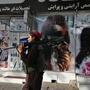 A Taliban fighter walks past a beauty salon with images of women defaced using spray paint in Shar-e-Naw in Kabul on August 18, 2021. (Photo by Wakil KOHSAR / AFP)