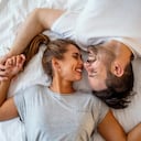 Chico y chica en un acogedor ambiente hogareño. Hombre y mujer felices acostados en la foto de stock del dormitorio. Vista superior de una pareja joven sonriente abrazándose en la cama por la mañana. Hermoso par de amantes abrazo y beso