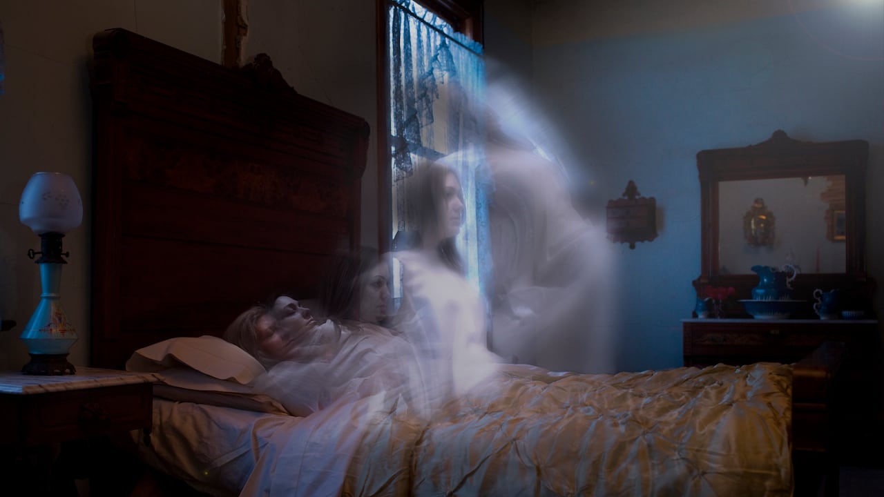 Anciana acostada en la cama con espíritu más joven subiendo desde el cuerpo hacia la fuente de luz