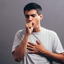 Hombre tosiendo en su primera, aislado sobre un fondo gris