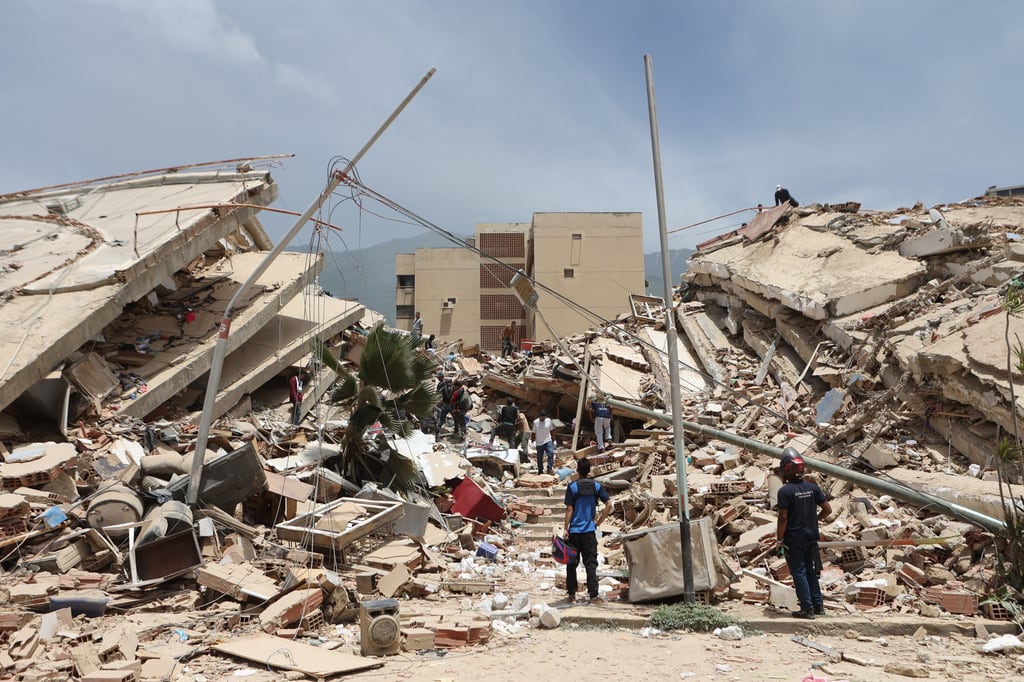 Residentes buscan entre los escombros de las casas dañadas durante el terremoto y varias réplicas que sacudieron La Guaira, Venezuela.