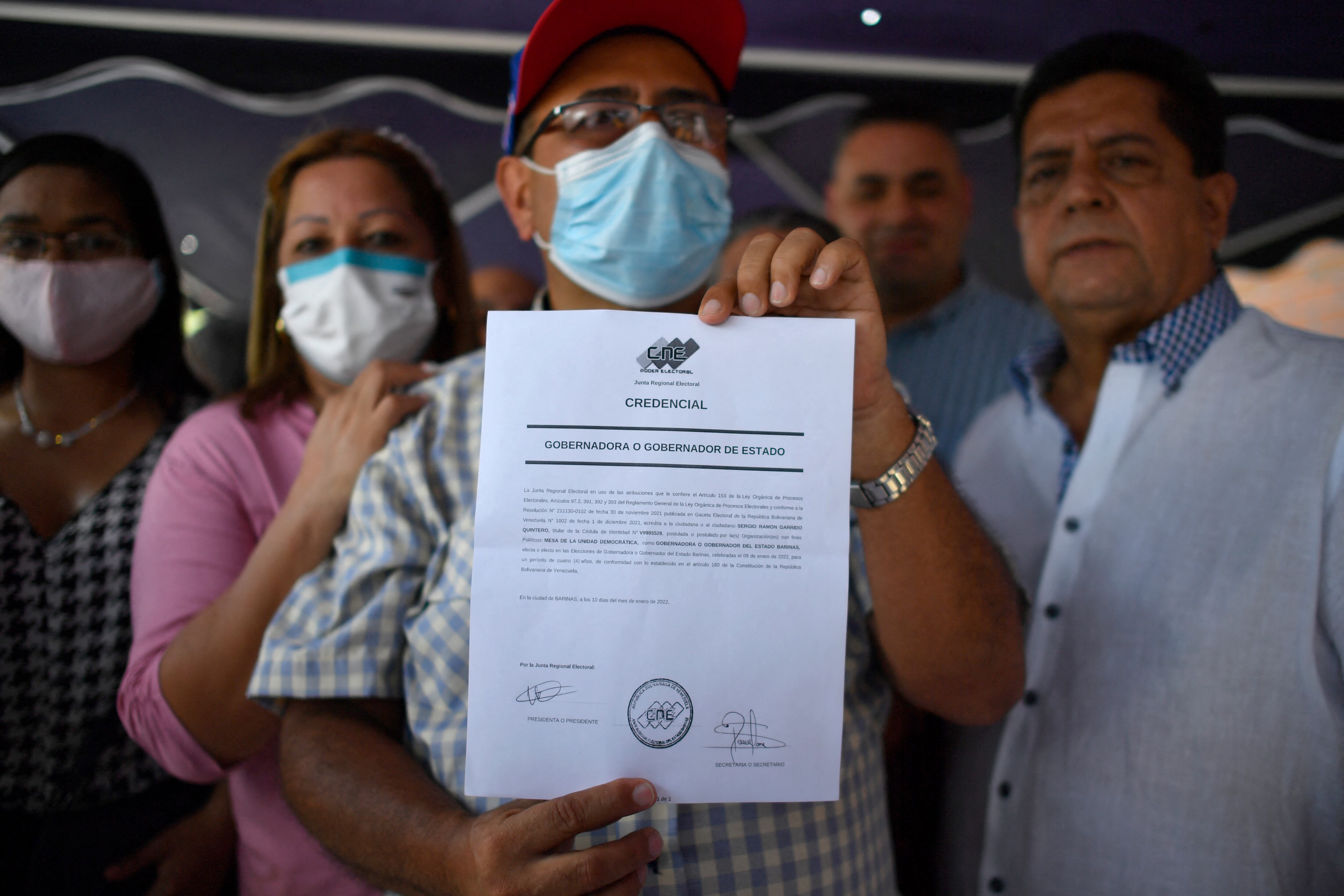 El gobernador electo del estado Barinas, Sergio Garrido, quien derrotó al candidato del oficialismo en la repetición del domingo de las elecciones a gobernador del estado Barinas, muestra el documento que lo acredita como gobernador durante su acreditación y proclamación por parte de la Oficina Regional Electoral del estado Barinas en representación del Consejo Nacional Electoral (CNE), en la sede del CNE en Barinas, Venezuela, el 10 de enero de 2022. - Según los primeros resultados oficiales anunciados la noche del domingo por el Consejo Nacional Electoral (CNE), Garrido obtuvo el 55,36 por ciento de los votos en el estado Barinas frente al 41,27 por ciento de Jorge Arreaza, de 48 años, quien se desempeñó como vicepresidente y canciller del país y yerno del difunto presidente Hugo Chávez. (Foto de Federico PARRA / AFP)