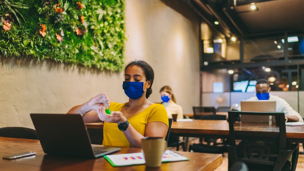 Los empresarios que trabajan en el espacio de oficina verde desinfectando las manos en el trabajo.