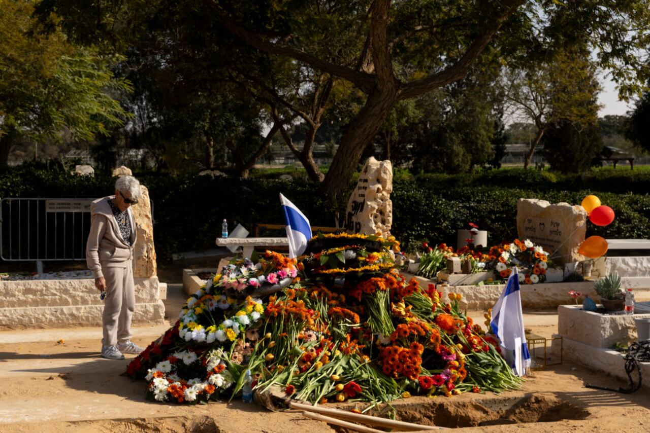 TZOHAR, ISRAEL - FEBRUARY 26: A woman pays tribute at the grave of slain hostages Shiri Bibas, Kfir Bibas and Ariel Bibas after their funeral on February 26, 2025 in Tzoahr Israel. A funeral is being held for former hostages Shiri Bibas and her two young sons, Ariel and Kfir, whose bodies were returned to Israel from Gaza last week. At the time of their abduction from Kibbutz Nir Oz on October 7, 2023, Shiri was 32, Ariel was four, and Kfir was nine months old. Their father, Yarden Bibas, 34, was also taken by Hamas militants, but was released alive as part of the ceasefire agreement on 1 February. (Photo by Amir Levy/Getty Images)