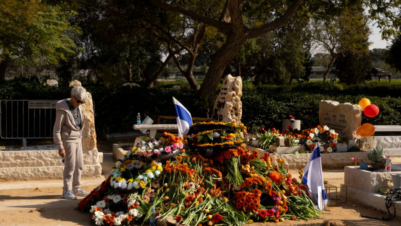 TZOHAR, ISRAEL - FEBRUARY 26: A woman pays tribute at the grave of slain hostages Shiri Bibas, Kfir Bibas and Ariel Bibas after their funeral on February 26, 2025 in Tzoahr Israel. A funeral is being held for former hostages Shiri Bibas and her two young sons, Ariel and Kfir, whose bodies were returned to Israel from Gaza last week. At the time of their abduction from Kibbutz Nir Oz on October 7, 2023, Shiri was 32, Ariel was four, and Kfir was nine months old. Their father, Yarden Bibas, 34, was also taken by Hamas militants, but was released alive as part of the ceasefire agreement on 1 February. (Photo by Amir Levy/Getty Images)