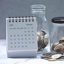 Febrluary 2024 calendar and glass jars with multicurrency coins. 2024 finance concept.