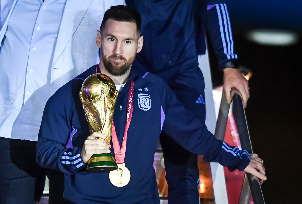 Lionel Messi sostiene el trofeo del Mundial de Fútbol a su llegada a Argentina.