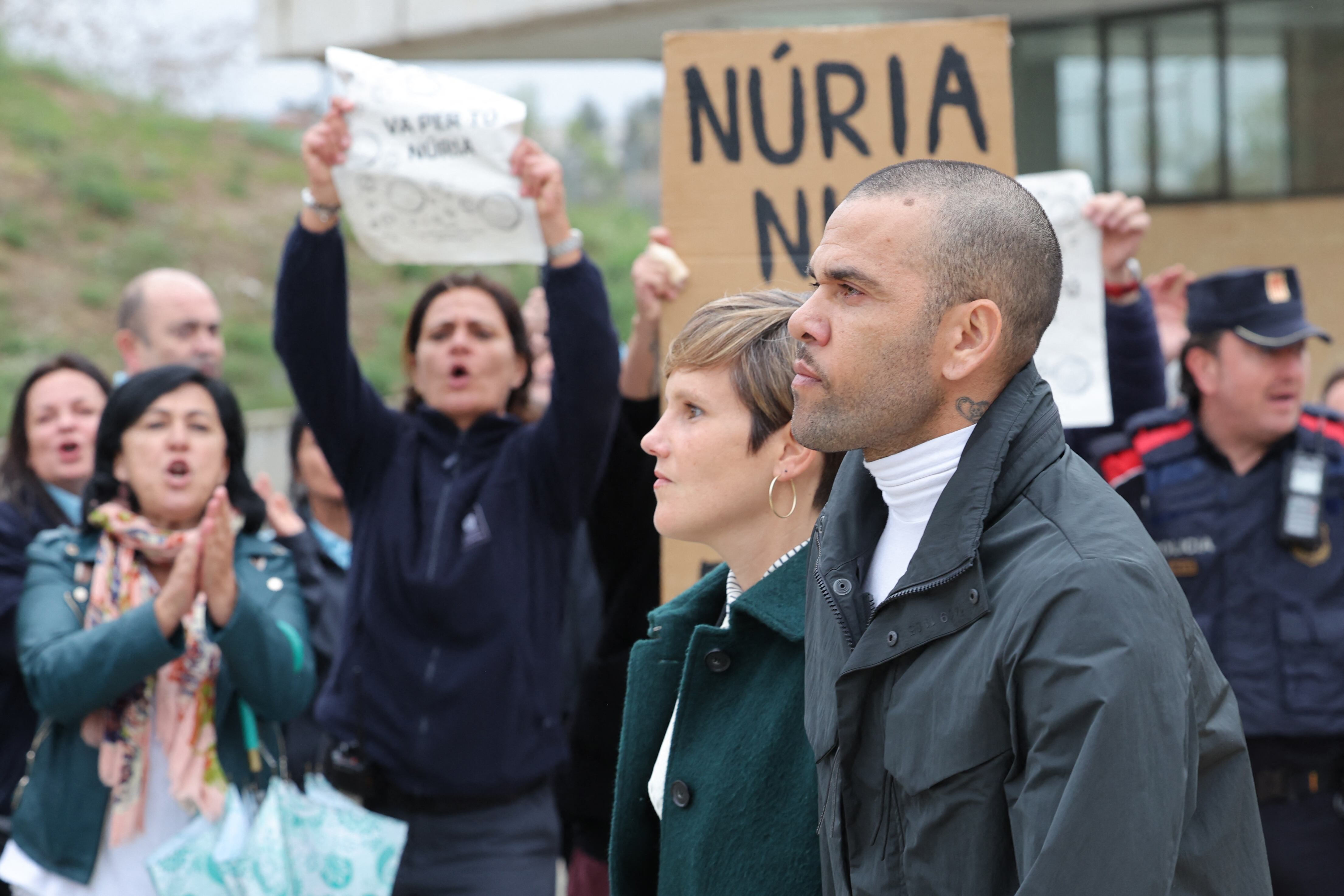 Prison workers unions' members protest over the killing of a cook by an inmate the week before, as convicted rapist and former Brazil international football player Dani Alves (R), flanked by his lawyer Ines Guardiola, leaves Brians 2 prison in San Esteban Sasroviras, near Barcelona, on March 25, 2024. Convicted rapist and former Brazil international Dani Alves left a jail in Barcelona on March 25, 2024 after posting the one-million-euro bail set by a Barcelona court to ensure his release pending appeal. Ex-Brazil star has been sentenced to 4.5 years in jail for rape on February 22, 2024. (Photo by LLUIS GENE / AFP)