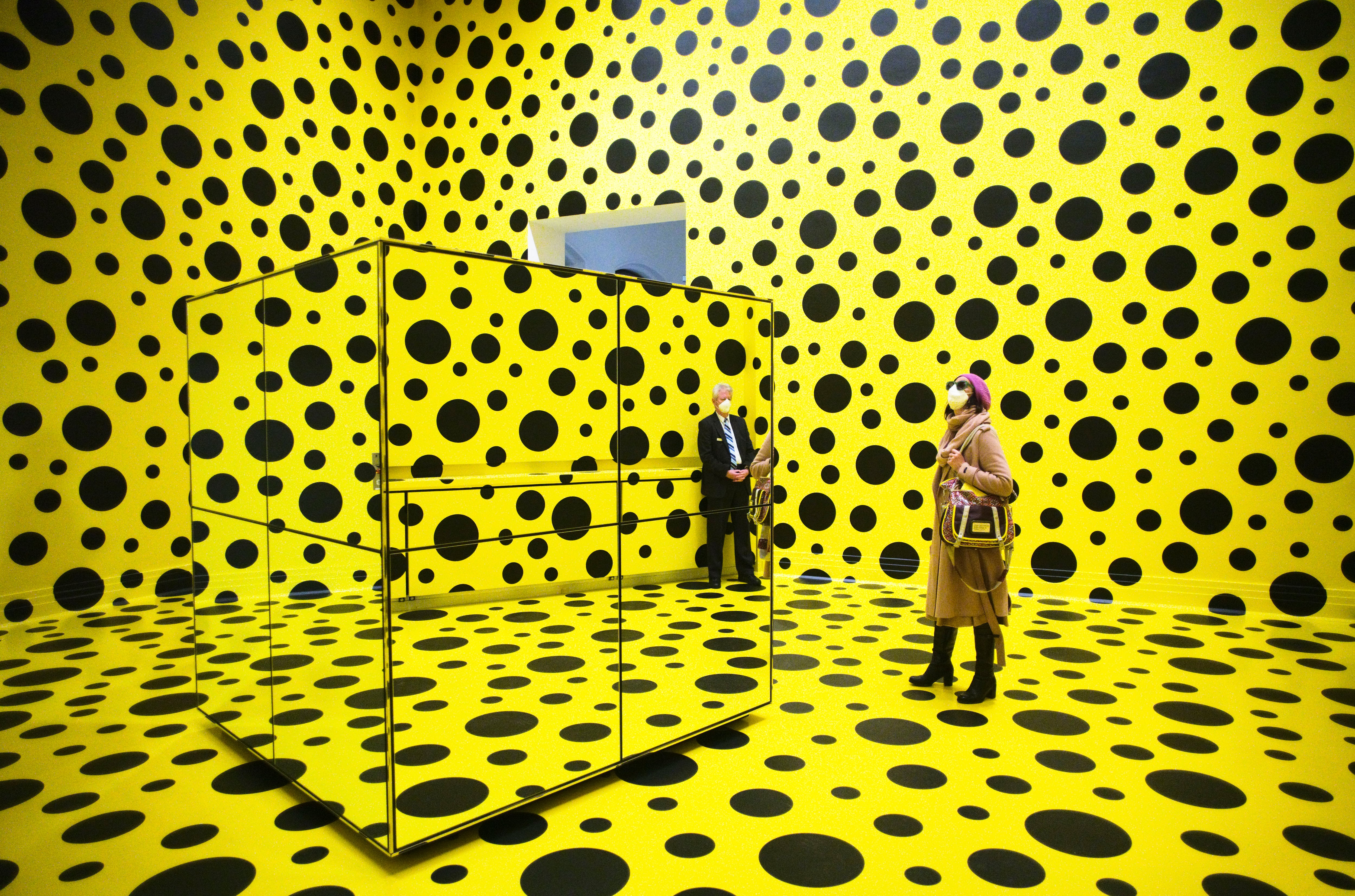 Un grupo de personas pasea por la obra de arte "Los espíritus de los calabacines descendieron a los cielos", de Yayoi Kusama, en la retrospectiva de la artista japonesa en el museo Martin Gropius Bau de Berlín, Alemania, el jueves 22 de abril de 2021.  AP Photo/Markus Schreiber