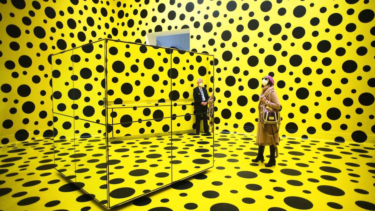 Un grupo de personas pasea por la obra de arte "Los espíritus de los calabacines descendieron a los cielos", de Yayoi Kusama, en la retrospectiva de la artista japonesa en el museo Martin Gropius Bau de Berlín, Alemania, el jueves 22 de abril de 2021. AP Photo/Markus Schreiber