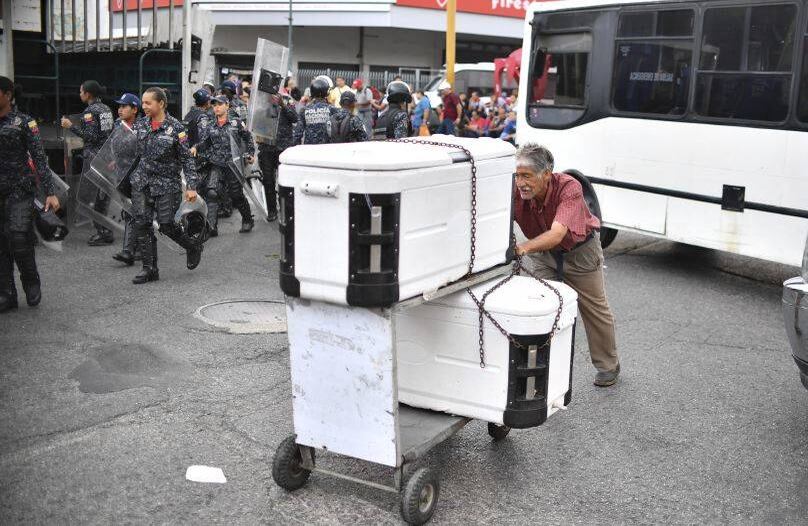  Un hombre empuja un carrito con refrigeradores mientras los policías de la Guardia Nacional Bolivariana son enviados a una estación de metro en Caracas, Venezuela. FOTO: Yuri CORTEZ/AFP