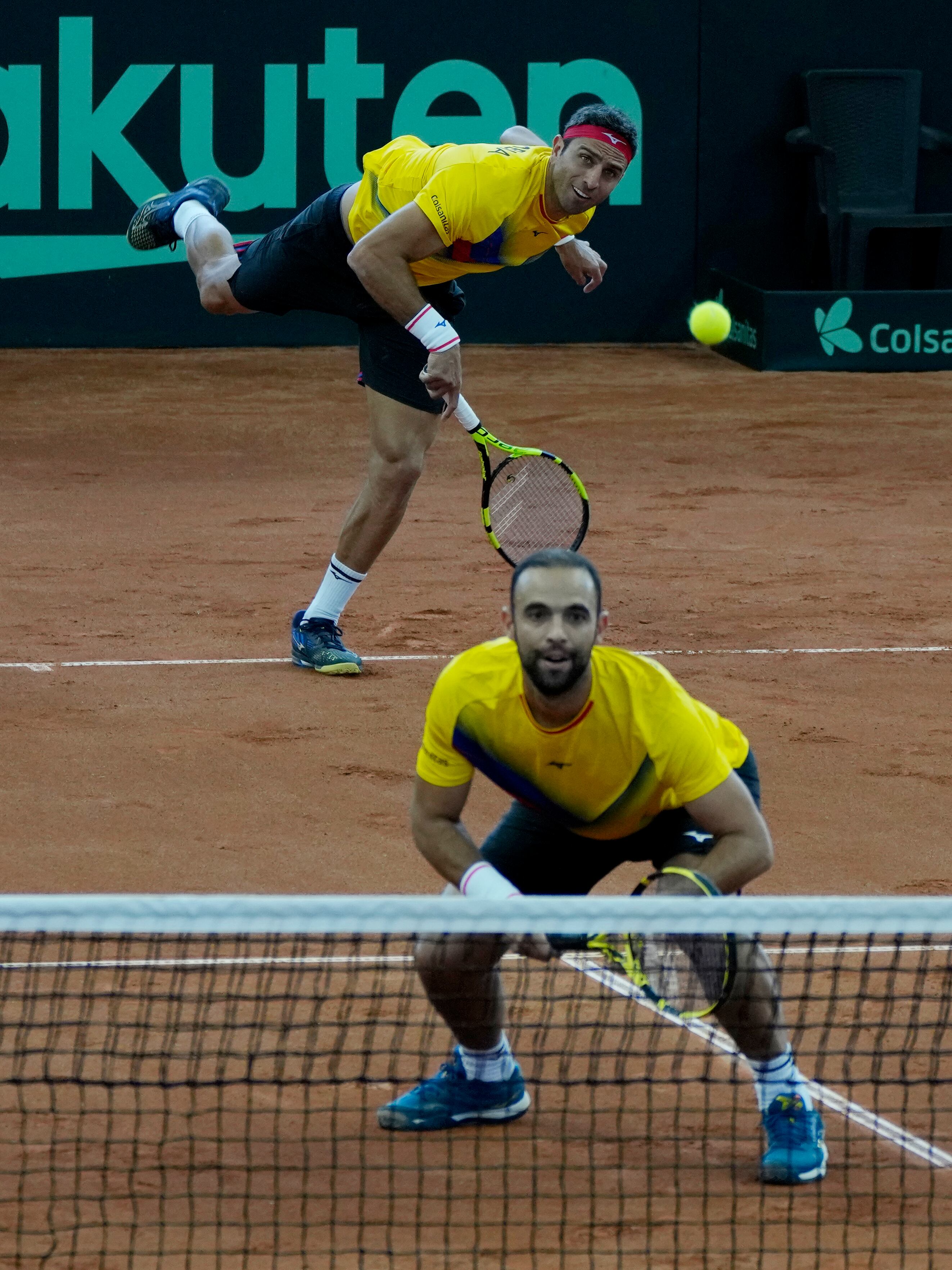 Colombia's Robert Farah, top, serves as teammate Juan Cabal, bottom watches during their Davis Cup qualification doubles match against Neal Skupski and Dan Evans of Britain, in Cota, Colombia, Saturday, Feb. 4, 2023. (AP Photo/Fernando Vergara)