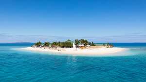 Hermosa isla pequeña en medio del océano Pacífico sur con cabañas de playa, palmeras, rodeada de hermosas aguas turquesas claras. Pequeño islote, Islas Mamanuca, Fiji, Melanesia, Oceanía