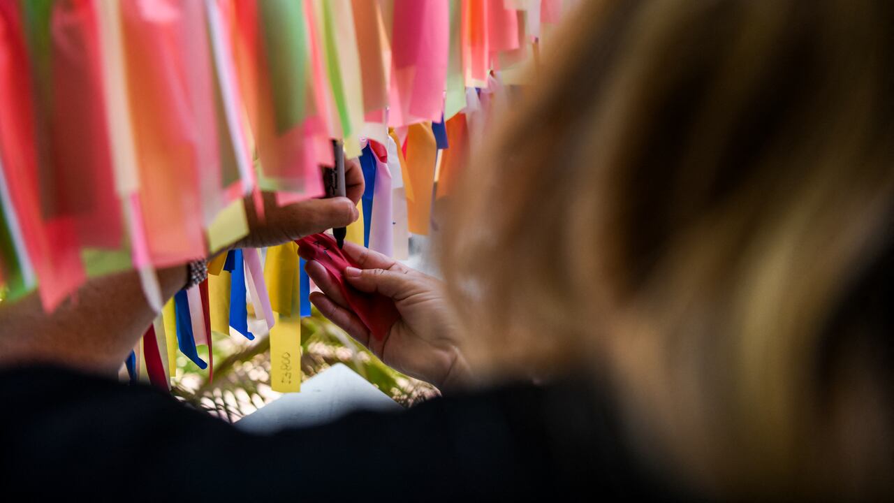 Cathy Tobias comenzó a atar una cinta a una cuerda por cada muerte de Covid-19 en Florida, no tenía idea de que todo su patio terminaría cubierto de colores. (Foto de CHANDAN KHANNA / AFP)