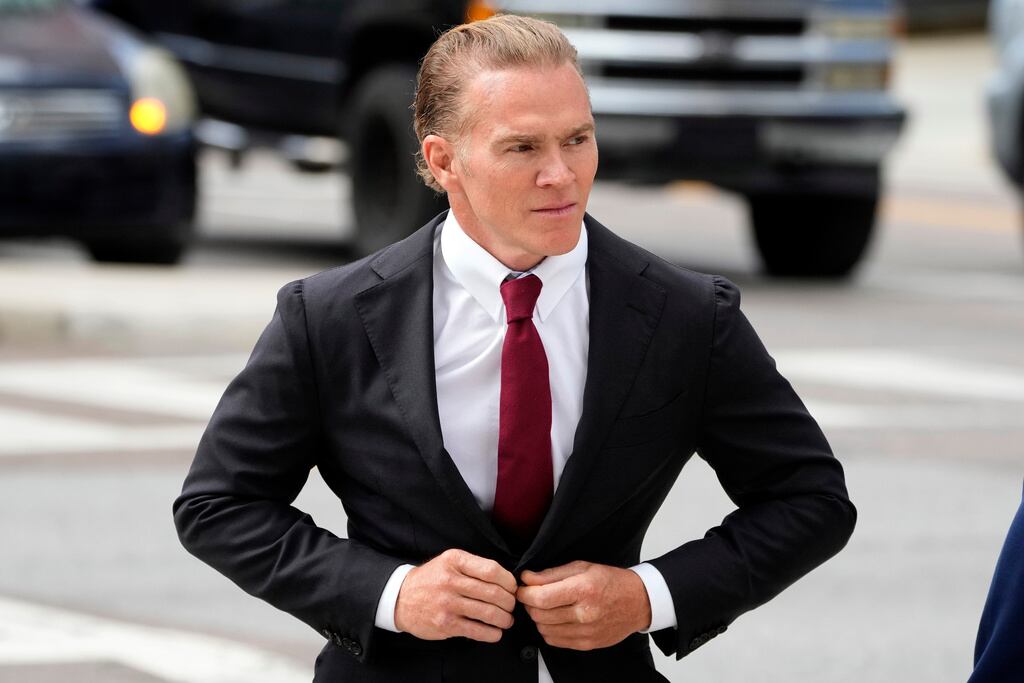 El ex boina verde Jordan Goudreau se abotona la chaqueta del traje mientras camina hacia el Tribunal Federal de los Estados Unidos para una audiencia de fianza en Tampa, Florida, el miércoles 29 de octubre de 2025.