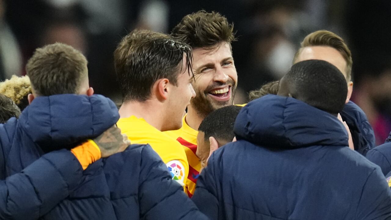 Gerard Piqué (centro, de frente) festeja con sus compañeros la goleada 4-0 de Barcelona al Real Madrid en la liga española el 20 de marzo del 2022 en el estadio Santiago Bernabéu de Madrid. (AP/Manu Fernández)