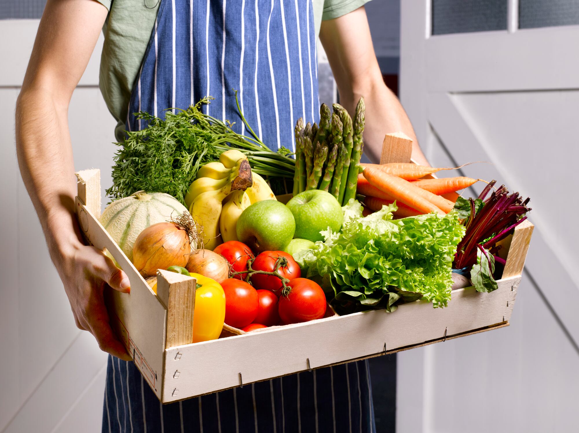 Hombre entregando caja de frutas y verduras