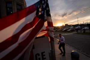 A voter looks at an informational leaflet passed out by a camping worker while entering a polling site on Election Day, Tuesday, Nov. 5, 2024, in Dearborn, Mich. (AP Photo/David Goldman)