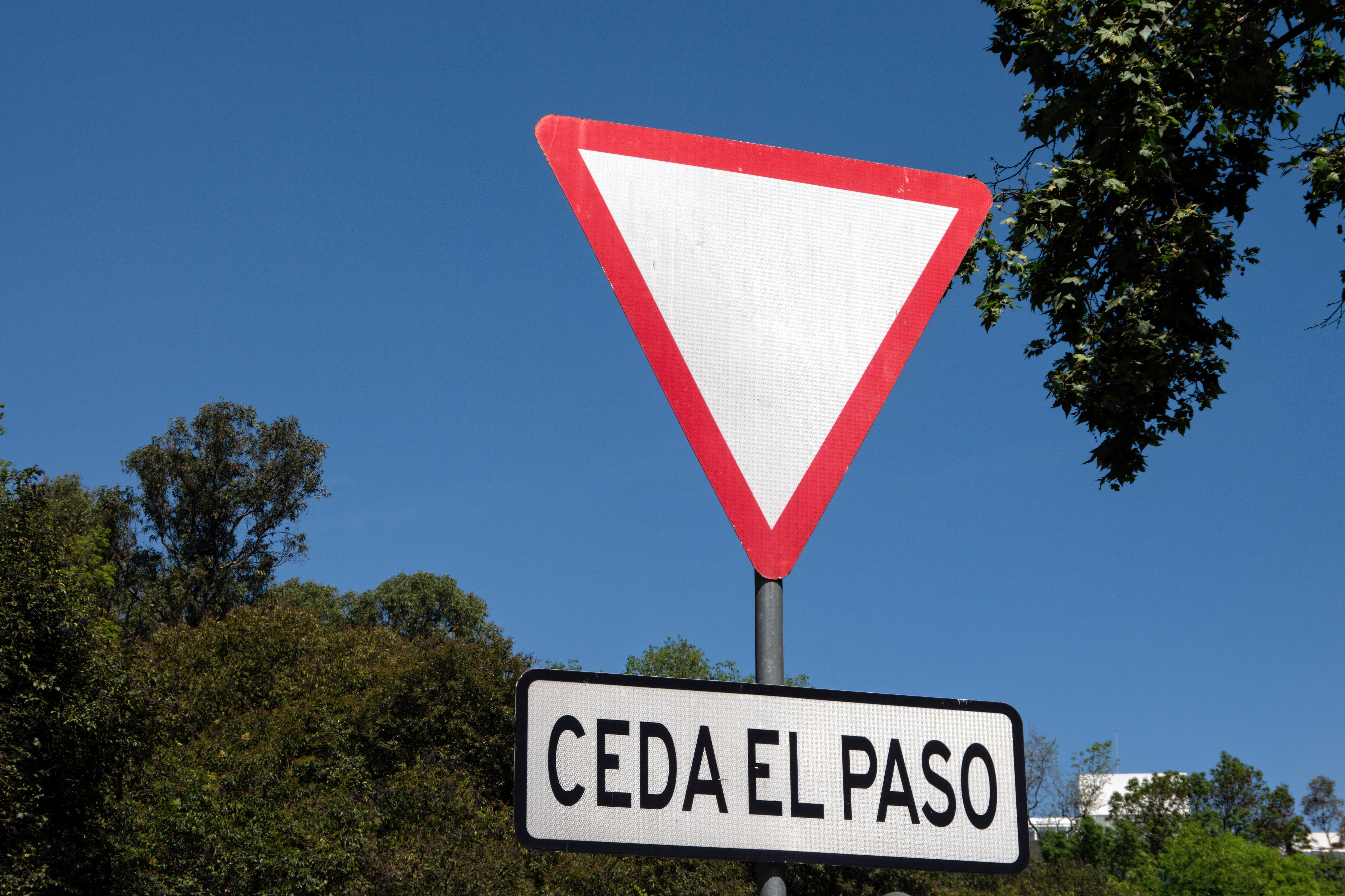 El triángulo invertido con borde rojo es una señal reglamentaria utilizada para reducir el riesgo de accidentes en intersecciones y cruces viales.