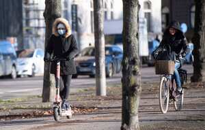 A woman rides an electric scooter wearing a protective mask, amid the continuous spread of the coronavirus disease, in Stockholm, Sweden, Friday Nov. 20, 2020, (Fredrik Sandberg / TT via AP)