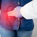 Síndrome de dolor en la enfermedad hepática. Examen hepatólogo. Una mujer le agarra el costado derecho por debajo de las costillas. Dolor en el higado.