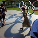 Transeúntes pasan frente a los anillos olímpicos en Tokio el 9 de junio del 2021. Hay una fuerte oposición a la realización de los Juegos Olímpicos, pero demasiados intereses en juego, que hacen que los organizadores insistan en realizar la justa en medio de una pandemia. (AP Photo/Eugene Hoshiko, File)