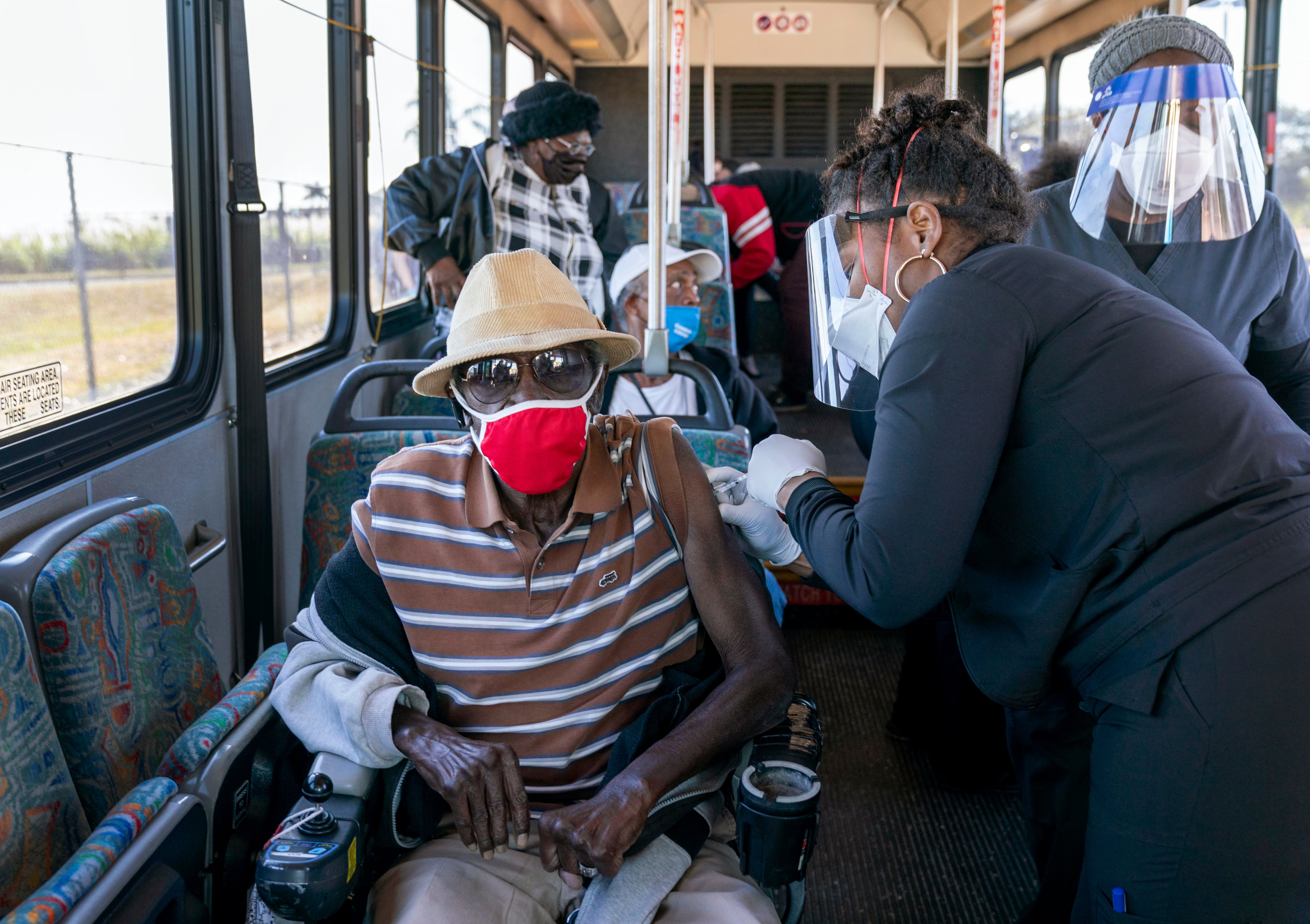 Una persona mayor recibe una vacuna COVID-19 de un trabajador de la salud después de llegar en un autobús a un sitio de vacunación en el Estadio Anquan Boldin en Pahokee, Florida, Estados Unidos.