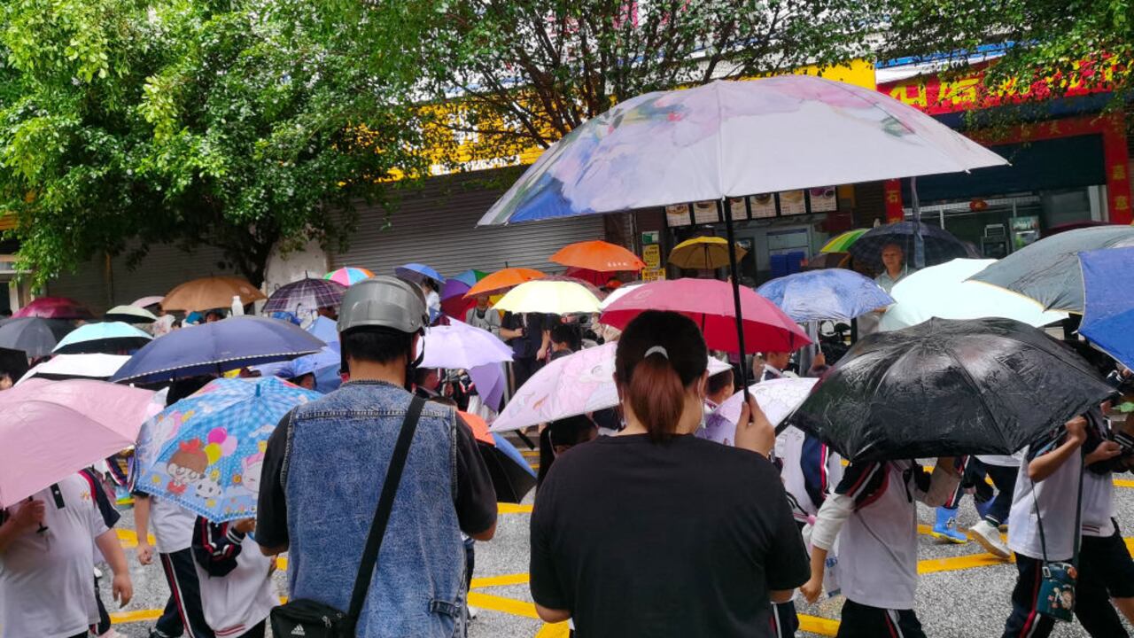 Los padres sostienen paraguas para recoger a los estudiantes en la puerta de la escuela mientras las clases de jardín de infantes se reanudan al mediodía en Qingyuan, provincia de Guangdong, en el sur de China, el 23 de abril de 202