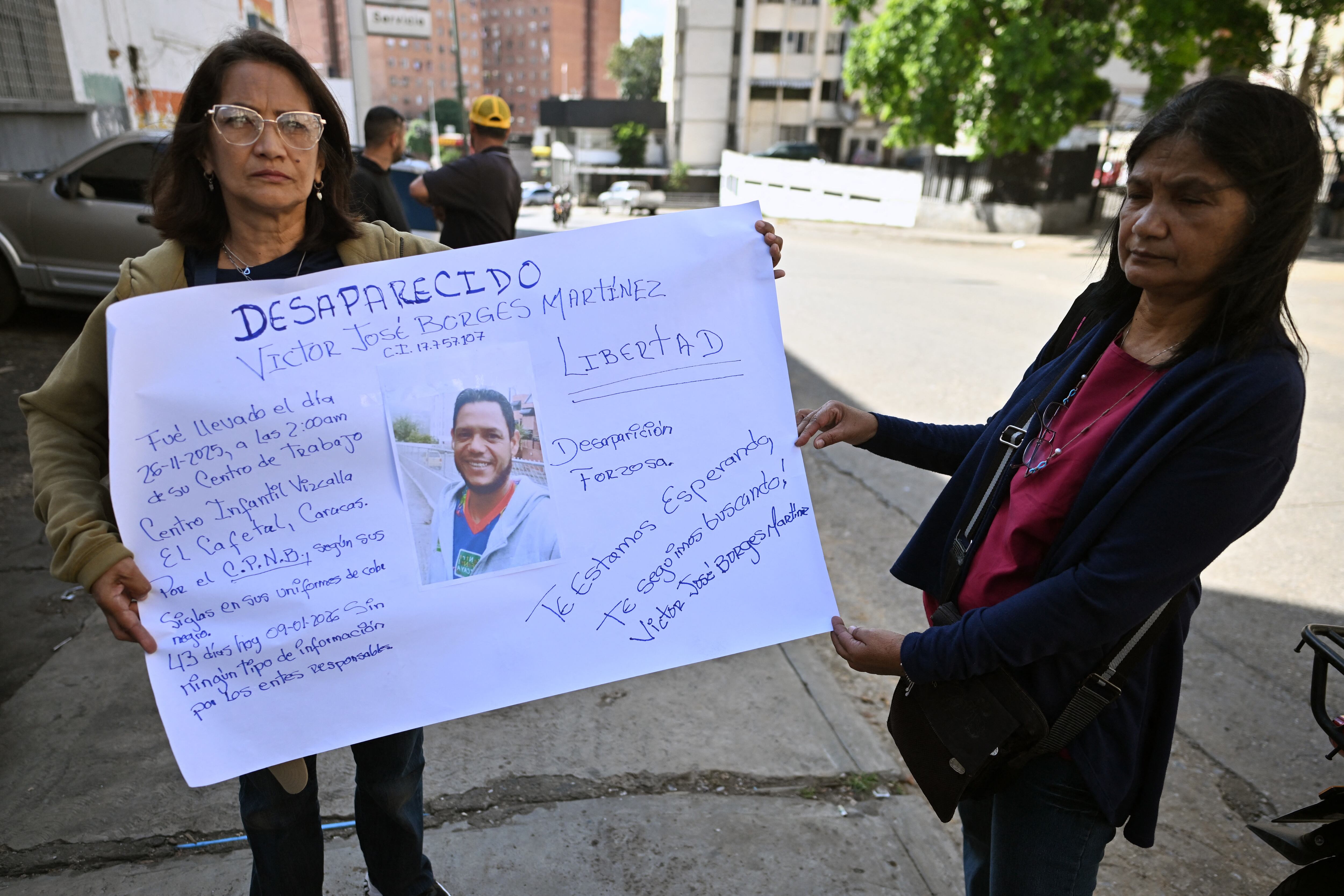 Familiares de un hombre desaparecido sostienen un cartel frente a El Helicoide —una prisión propiedad del gobierno venezolano y utilizada para presos comunes y políticos del Servicio Bolivariano de Inteligencia Nacional (SEBIN)— en Caracas el 9 de enero de 2026. Las autoridades venezolanas están liberando a un gran número de presos, algunos de ellos extranjeros.