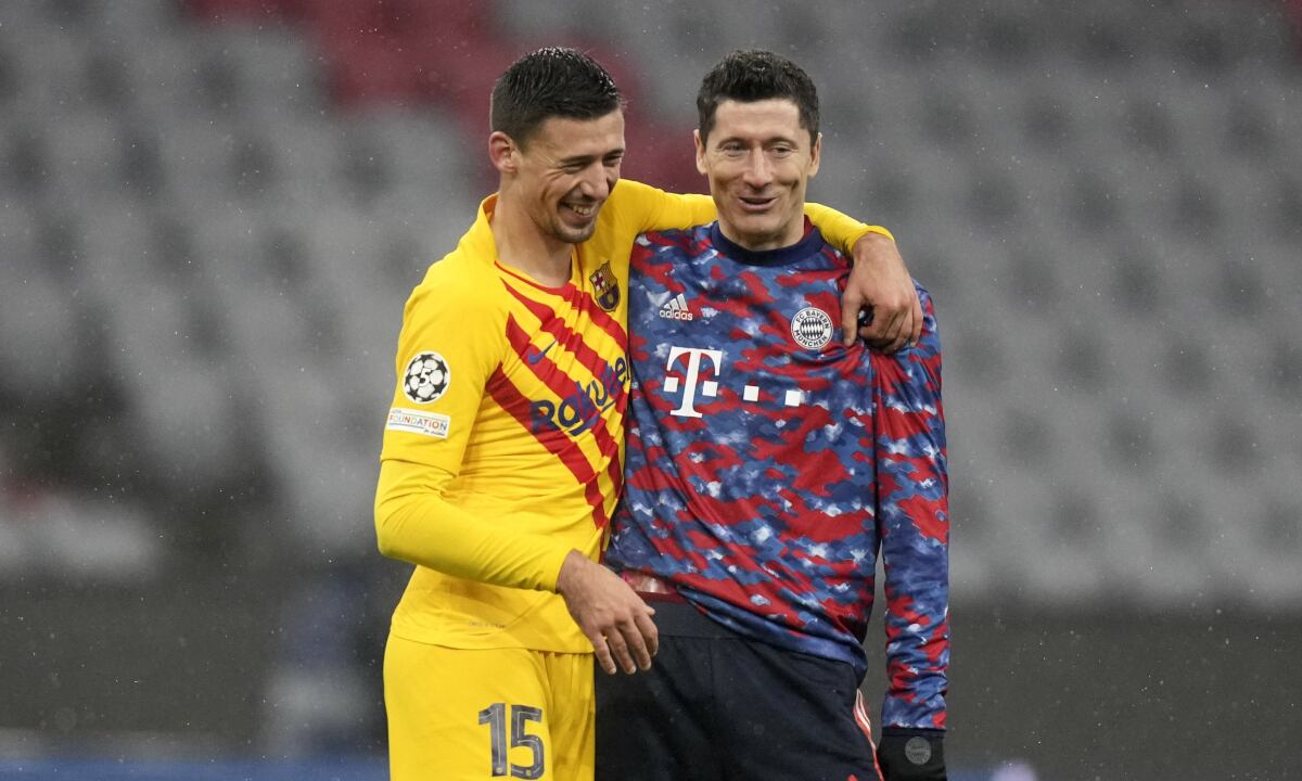 Barcelona's Clement Lenglet, left, and Bayern's Robert Lewandowski laugh after the Champions League group E soccer match between Bayern Munich and FC Barcelona in Munich, Germany, Wednesday, Dec. 8, 2021. Bayern won 3-0. (AP/Matthias Schrader)