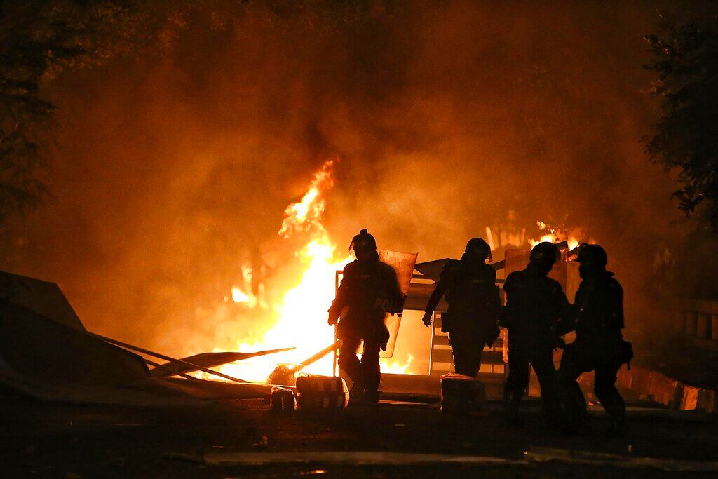 Riot police walk towards a burning barricade set up by protesters during a national strike to protest government-proposed tax reform, in Cali, Colombia, Friday, April 30, 2021. (AP Photo/Andres Gonzalez)