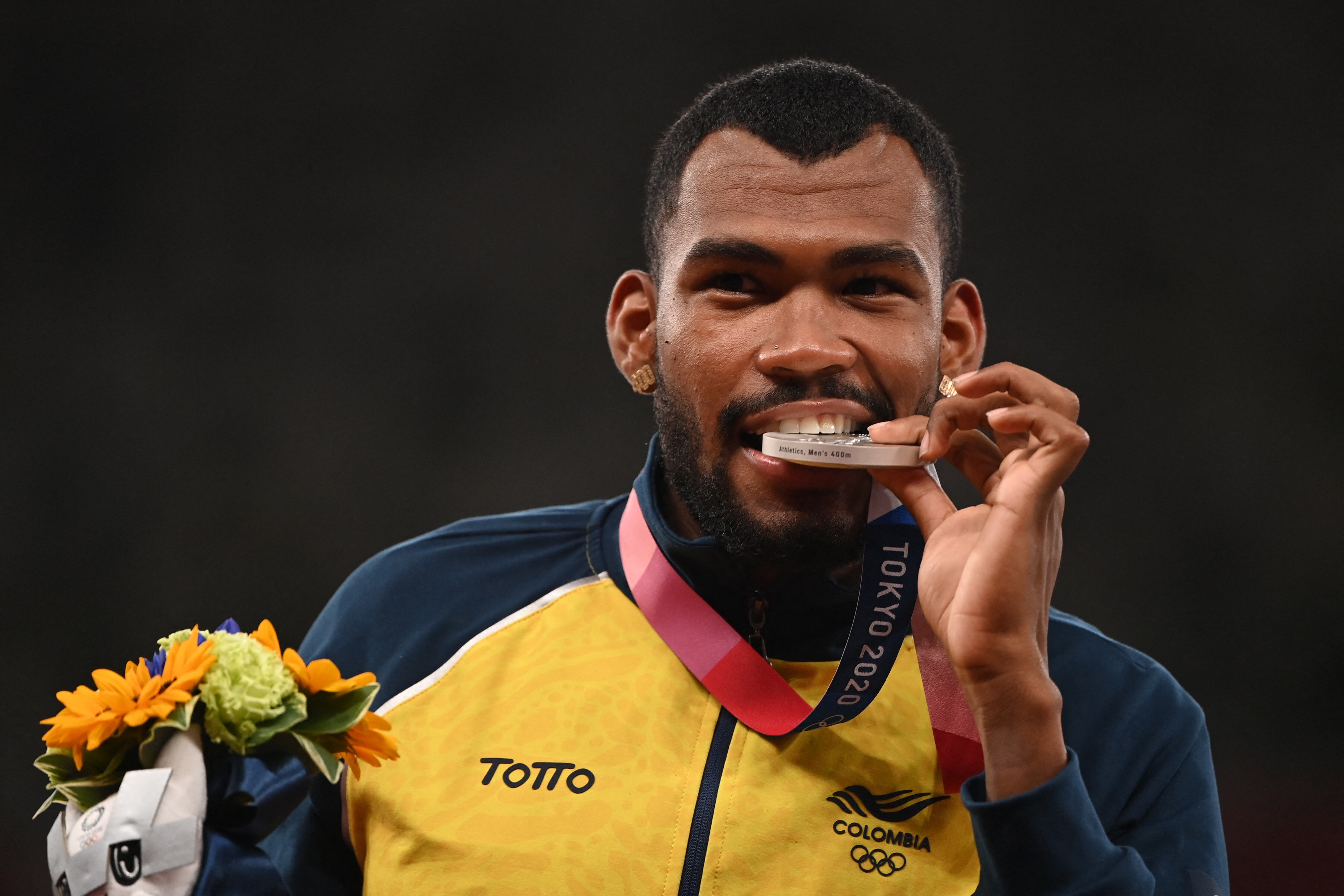 El colombiano Anthony José Zambrano, medallista de plata, muerde su medalla durante la ceremonia de entrega de medallas de los 400 metros masculinos durante los Juegos Olímpicos de Tokio 2020 en el Estadio Olímpico de Tokio el 6 de agosto de 2021 (Foto de Ina FASSBENDER / AFP).