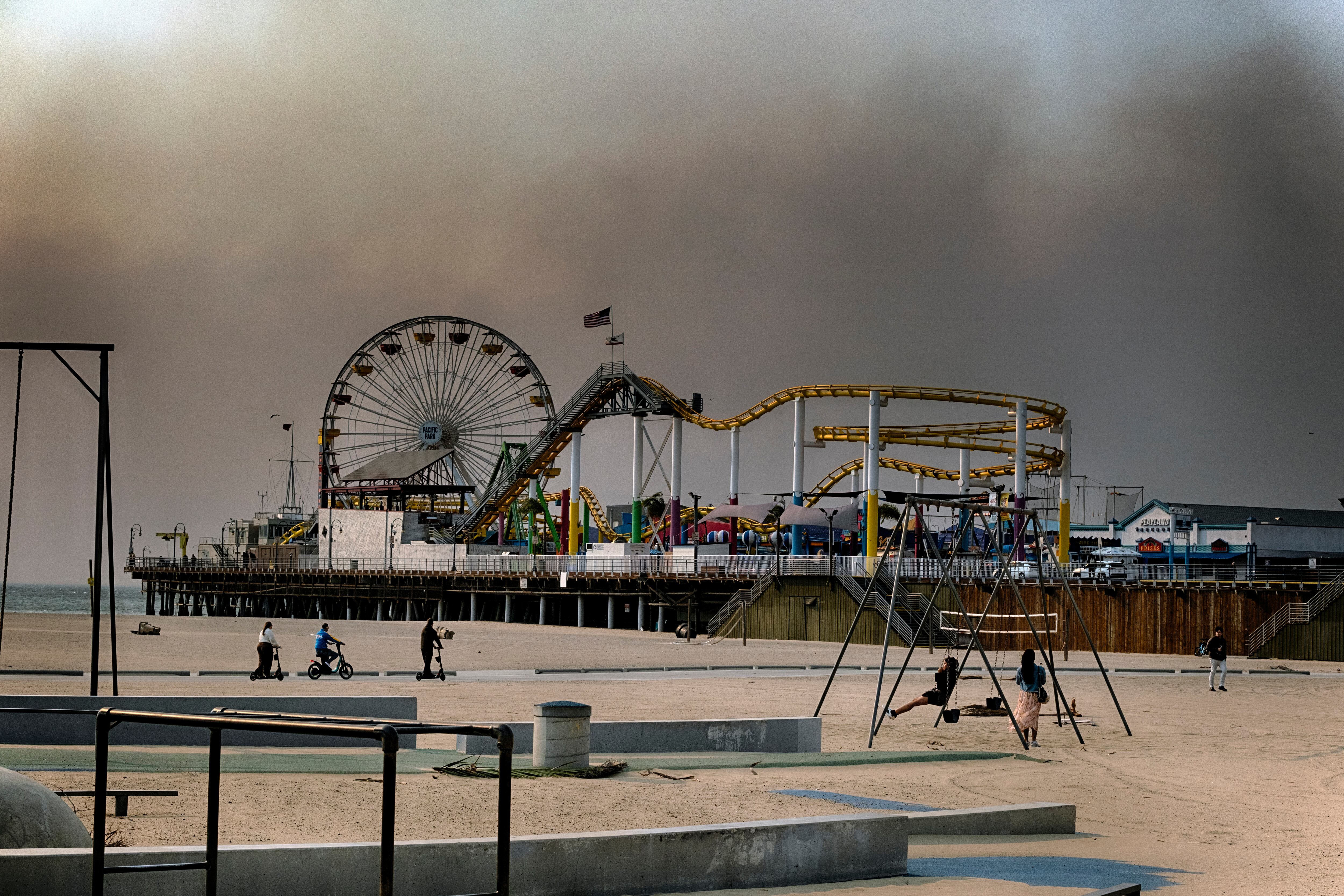People play on the beach as smoke from a wildfire blows over the Santa Monica pier in Santa Monica, Calif., on Wednesday, Jan. 8, 2025. (AP Photo/Richard Vogel)