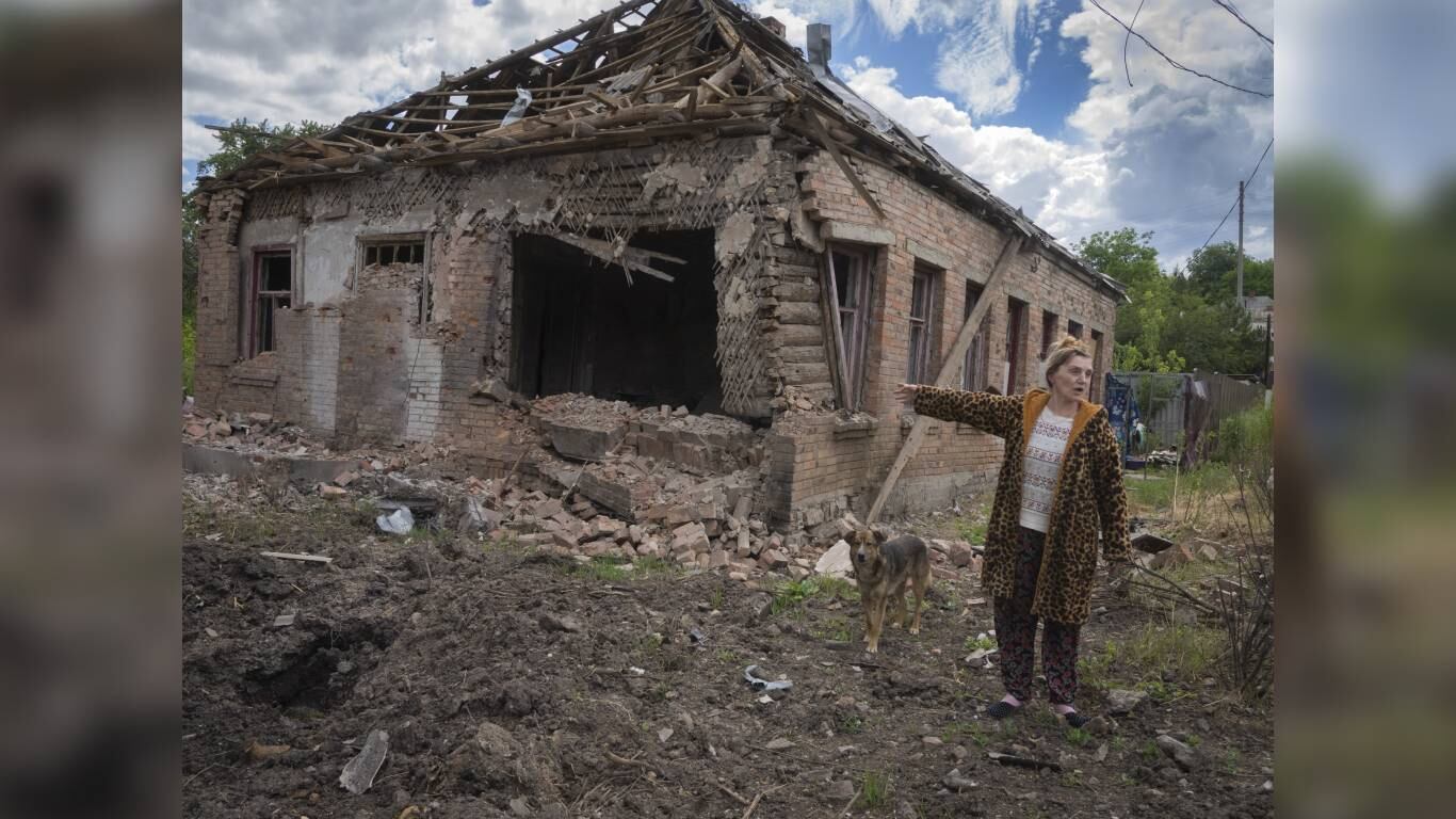 La residente local Tetyana apunta a su casa dañada por el cañoneo ruso en Bajmut, en la región de Donetsk, Ucrania, el viernes 24 de junio de 2022. Foto: AP/Efrem Lukatsky.