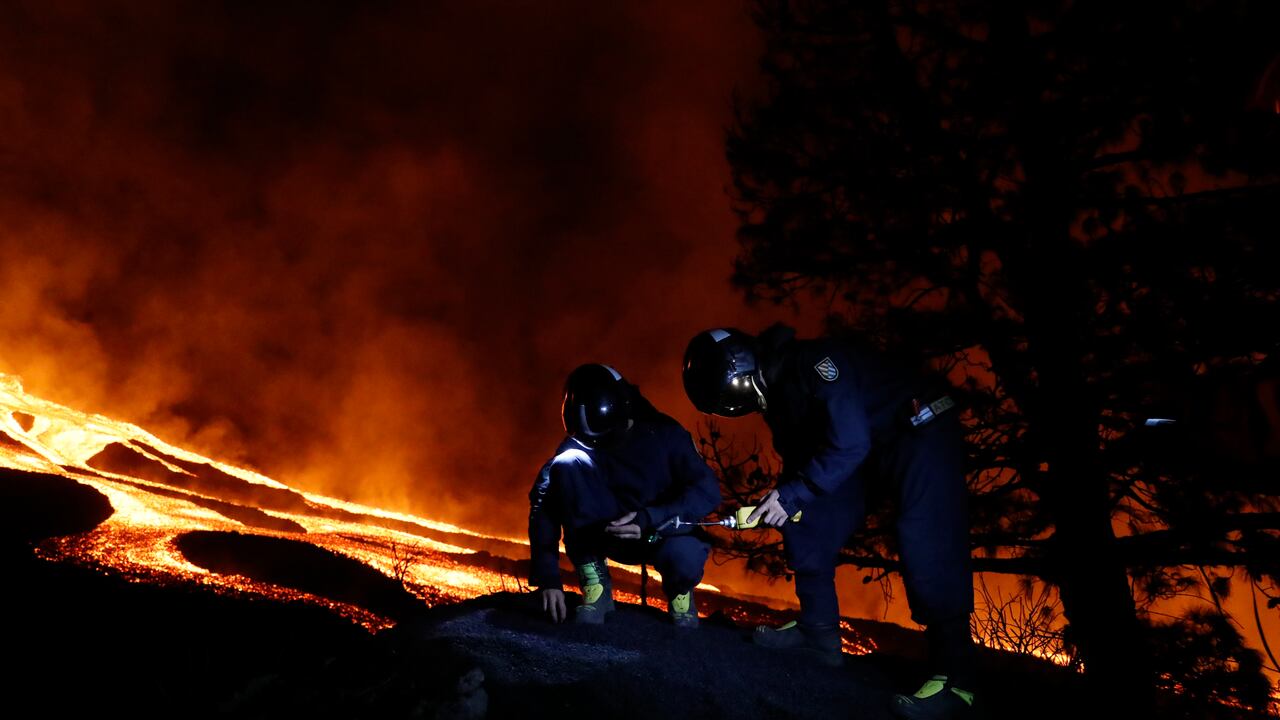 Military Emergency Unit personal take gas reading measurements near a volcano on the Canary island of La Palma, Spain, in the early hours of Tuesday Sept. 28, 2021. Lava flowing from an erupting volcano on the Spanish island of La Palma has picked up pace on its way to the sea. Officials say it is now within about 800 meters (875 yards) of the shoreline. When the molten rock eventually meets the sea water it could trigger explosions and toxic gas. (Luismi Ortiz/UME, via AP)