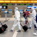 Una mujer, acompañada de un niño, mira cómo una tripulación de la aerolínea que lleva todo el equipo de protección personal contra COVID-19 camina a través de la terminal internacional en el Aeropuerto Internacional de Los Ángeles, el martes 17 de noviembre de 2020. Foto: Keith Birmingham / The Orange County Register vía AP
