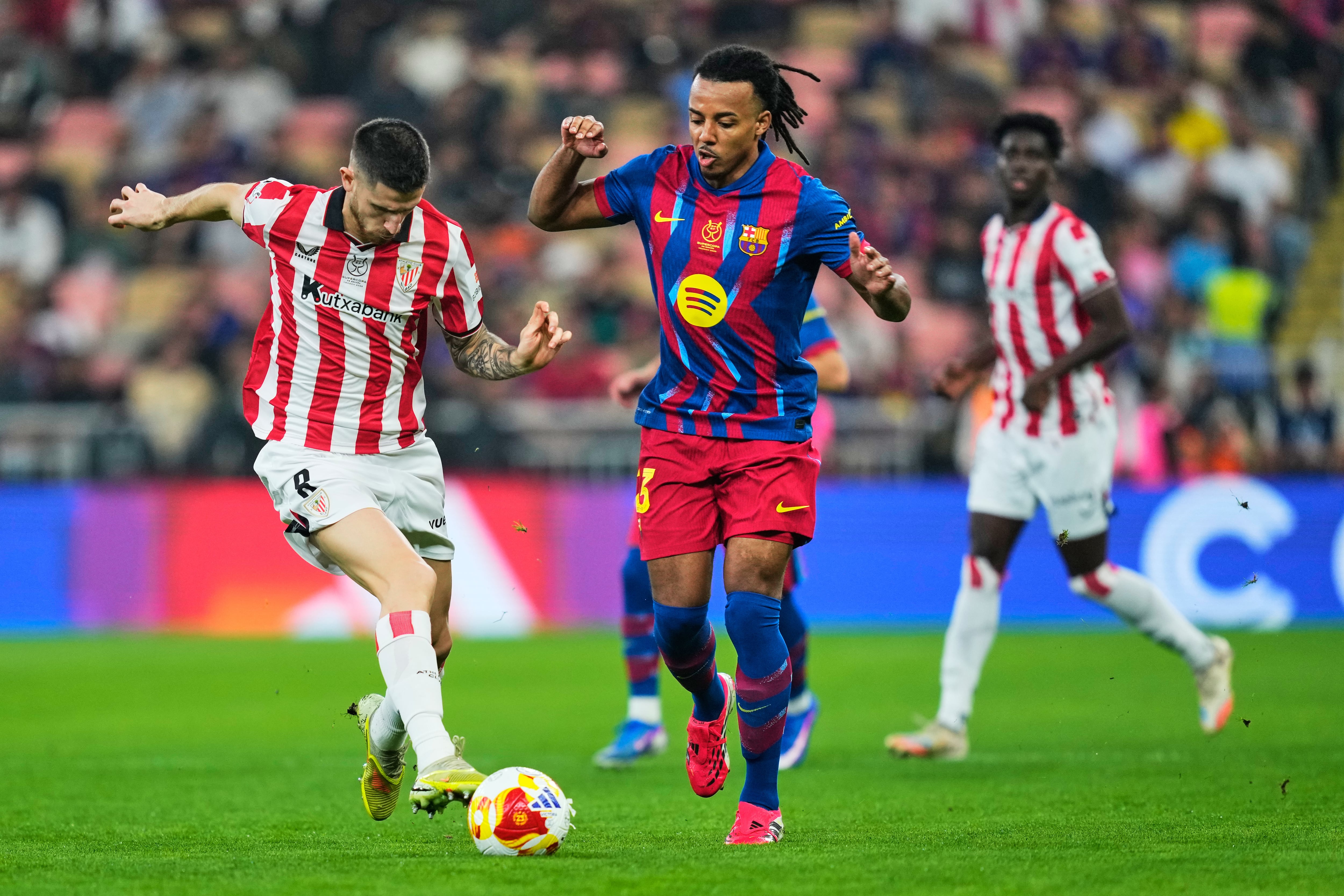 Athletic Bilbao's Oihan Sancet, left, duels for the ball with Barcelona's Jules Kounde during the Spanish Super Cup semifinal soccer match at King Abdullah Sports City Stadium in Jeddah, Saudi Arabia, Wednesday, Jan. 7, 2026. (AP Photo/Altaf Qadri)