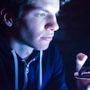 16 years old boy playing with smartphone in the dark