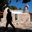 Un vecino pasa junto a una capilla ortodoxa griega dañada por un fuerte sismo en el poblado de Arcalochori, en la isla sureña de Creta, Grecia, el lunes 27 de septiembre de 2021. (AP Foto/Harry Nikos)