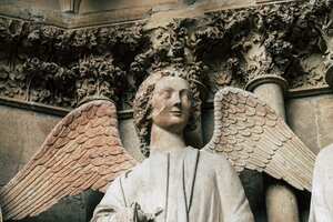 Closeup of a statue on the exterior facade of the Notre Dame de Reims cathedral in the afternoon