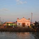 Un grupo de jóvenes juega fútbol en una cancha de tierra frente a la iglesia en Nueva Venecia.