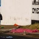 A couple walks past a body covered with a blanket after protests in the area, in Johannesburg, South Africa, Sunday, July 11, 2021. Protests have spread from the KwaZulu Natal province to Johannesburg against the imprisonment of former South African President Jacob Zuma who was imprisoned last week for contempt of court. (AP Photo/Themba Hadebe)