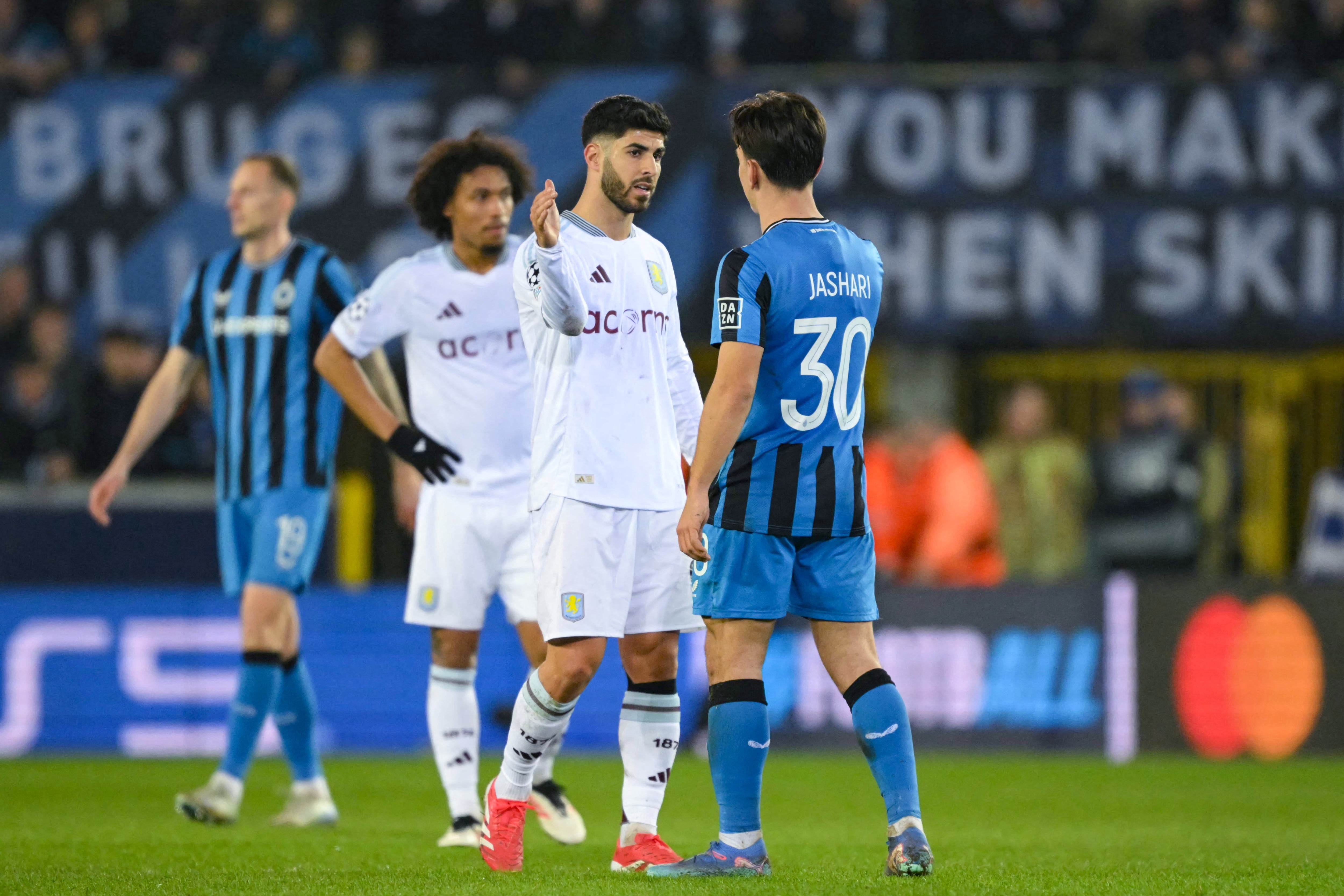 El delantero español del Aston Villa #21 Marco Asensio (L) le da la mano al centrocampista suizo del Club Brugge #30 Ardon Jashari después de ganar el partido de ida de octavos de final de la Liga de Campeones de la UEFA entre el Club Brugge KV y el Aston Villa FC en el estadio Jan Breydel de Brujas, el 4 de marzo de 2025.