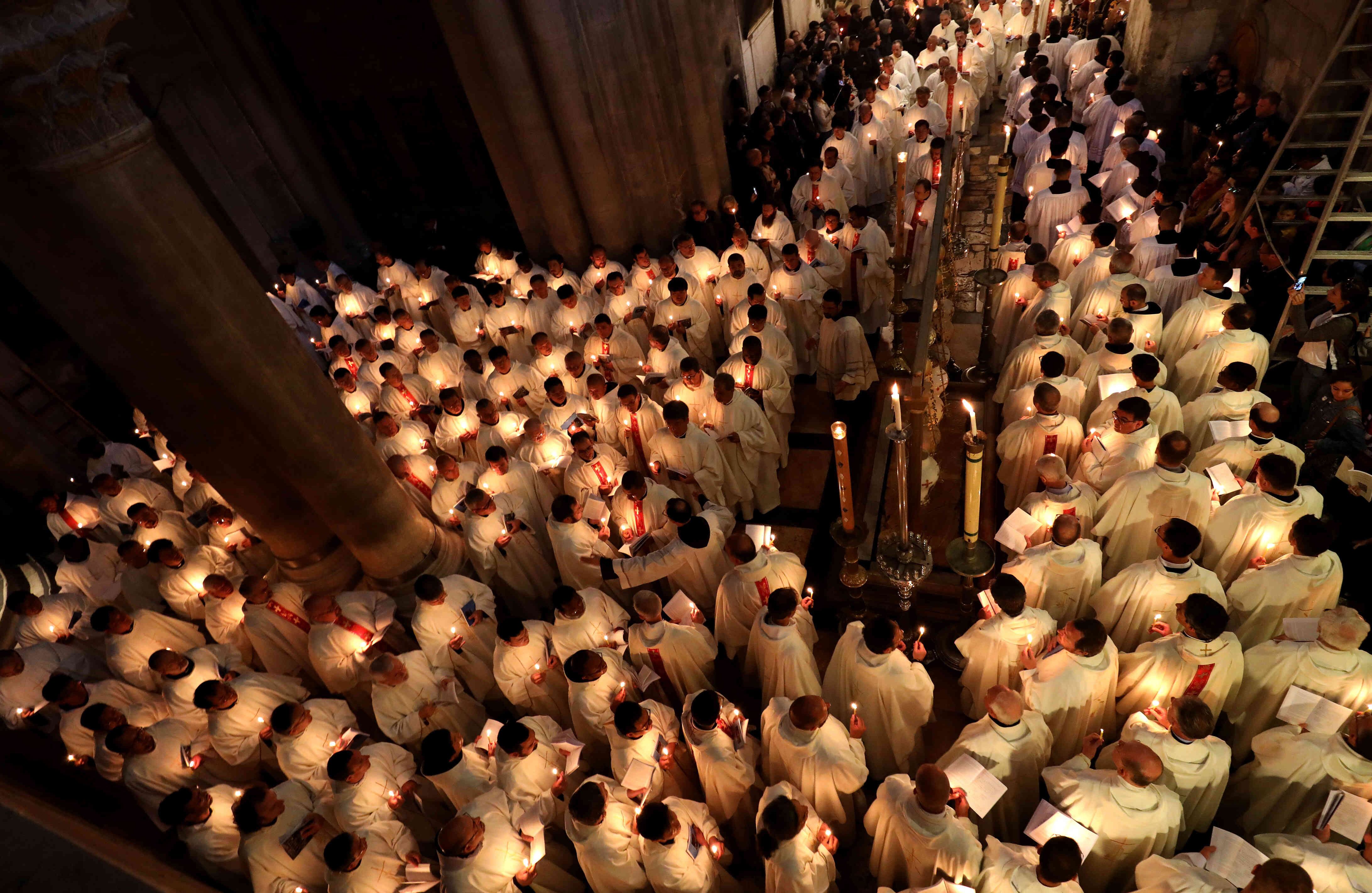 Los miembros del clero católico romano sostienen las velas mientras rodean la piedra de la Unción durante el Jueves Santo. Procesión de Pascua en la iglesia del Santo Sepulcro en la Ciudad Vieja de Jerusalén el 18 de abril de 2019, tradicionalmente se cree que es el lugar de la crucifixión y resurrección de Cristo . TIBBON GALI / AFP  