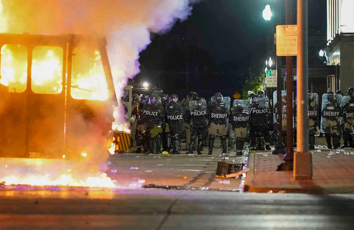 La policía se para cerca de un camión de basura en llamas durante las protestas, el lunes 24 de agosto de 2020, en Kenosha, Wisconsin, provocadas por el tiroteo de Jacob Blake por parte de un oficial de policía de Kenosha un día antes. Foto: Morry Gash / AP 
