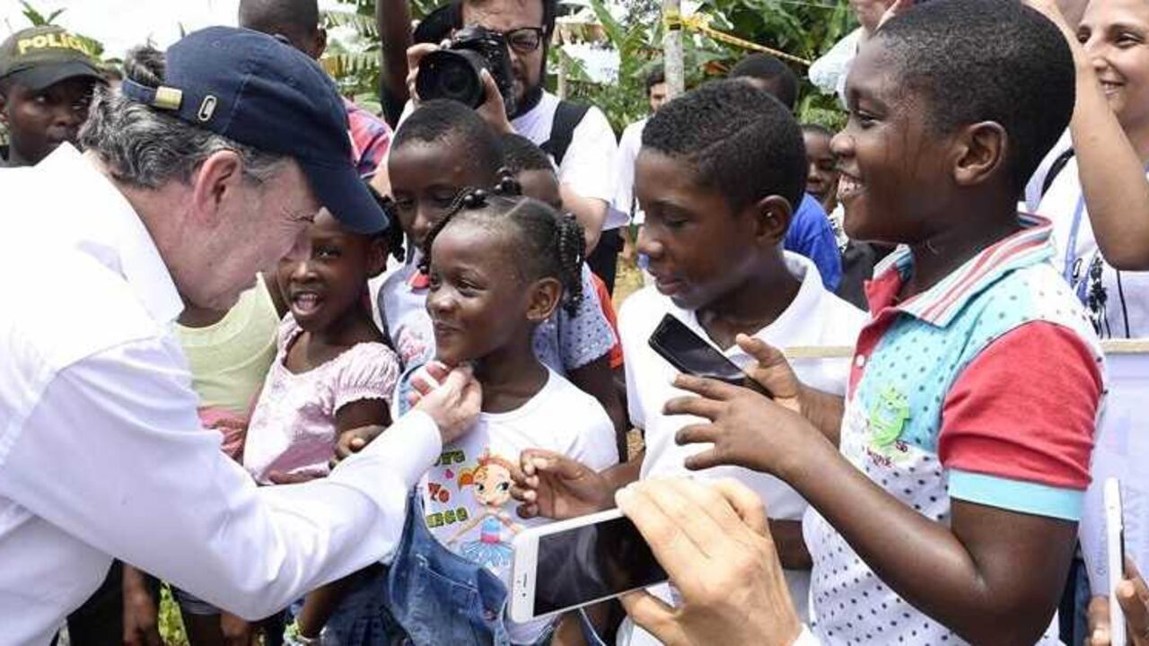 Juan Manuel Santos saludando este domingo 9 de octubre de 2016 a unos niños que lo recibieron en Bojayá (Chocó), una de las poblaciones que más ha sufrido el conflicto armado en Colombia, antes de asistir a una misa. Esta es la primera salida que realiza el presidente Santos luego de que le fuera otorgado el premio Nobel de la Paz 2016 y anunciar que donará los ocho millones de coronas suecas (unos US$950.000) que recibirá como parte del Premio Nobel de Paz que obtuvo el pasado viernes, para que las víctimas sean reparadas. Presidencia/EFE