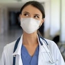 Retrato de una doctora pensativa que trabaja en el hospital usando una máscara facial para evitar los conceptos pandémicos COVID-19 â