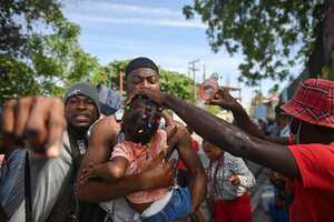 Protestors attend to a little girl exposed to teargas fired by police during a demonstration to demand better wages and working conditions in Port-au-Prince on May 9, 2023. Employees in the clothing manufacturing sector took part in a demonstration to demand a minimum of 2,500 gourdes ($16) a day. (Photo by Richard PIERRIN / AFP)