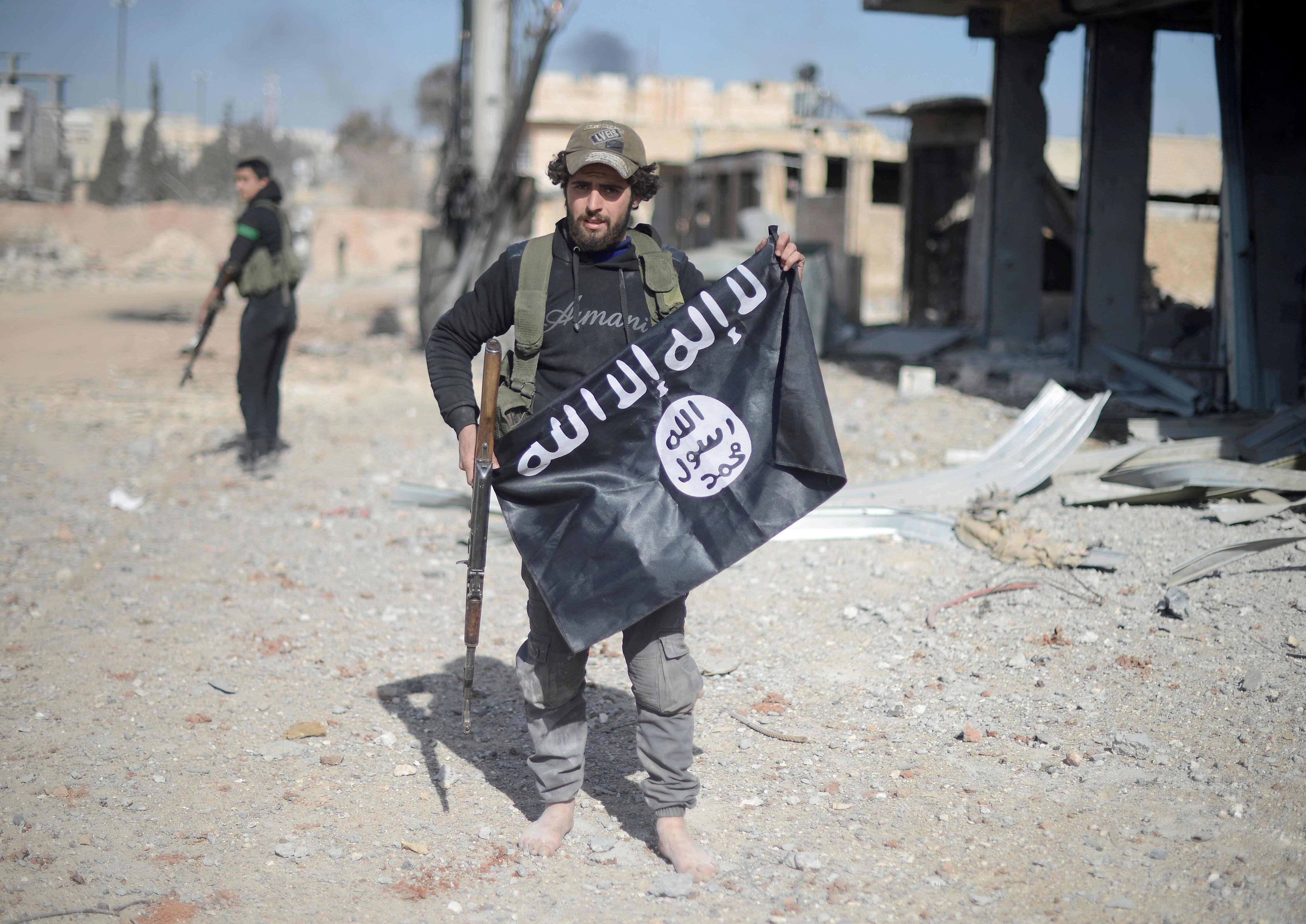 Miembros del Ejército Sirio Libre retiran las banderas de Daesh mientras avanzan hacia el centro del distrito de Al-Bab durante la "Operación Escudo del Éufrates" en Alepo